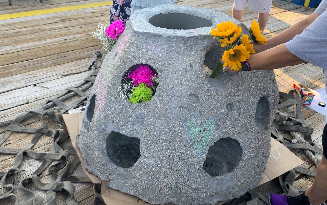 family placing flowers into reef ball