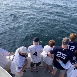 family in Yankees jerseys spreading flowers in the ocean