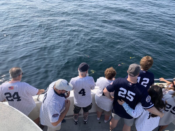 family in Yankees jerseys spreading flowers in the ocean