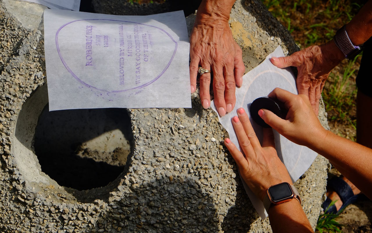 family making chalk rubbing of bronze placard on reef ball, in Ocean City, NJ