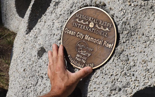 hand touching bronze placard on a new reef ball near Ocean City, NJ